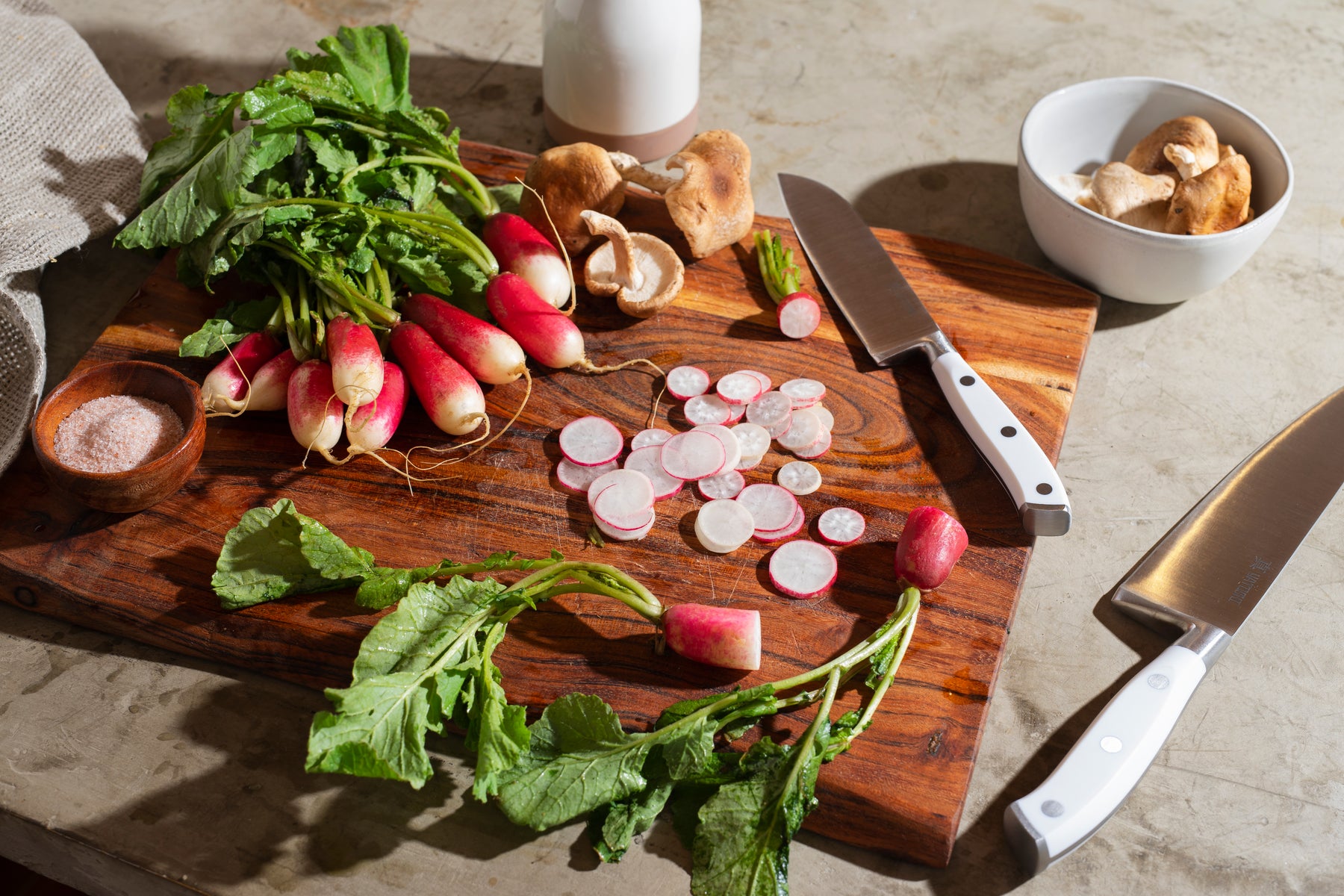 White ABS chef knife and santoku knife on cutting board with radishes