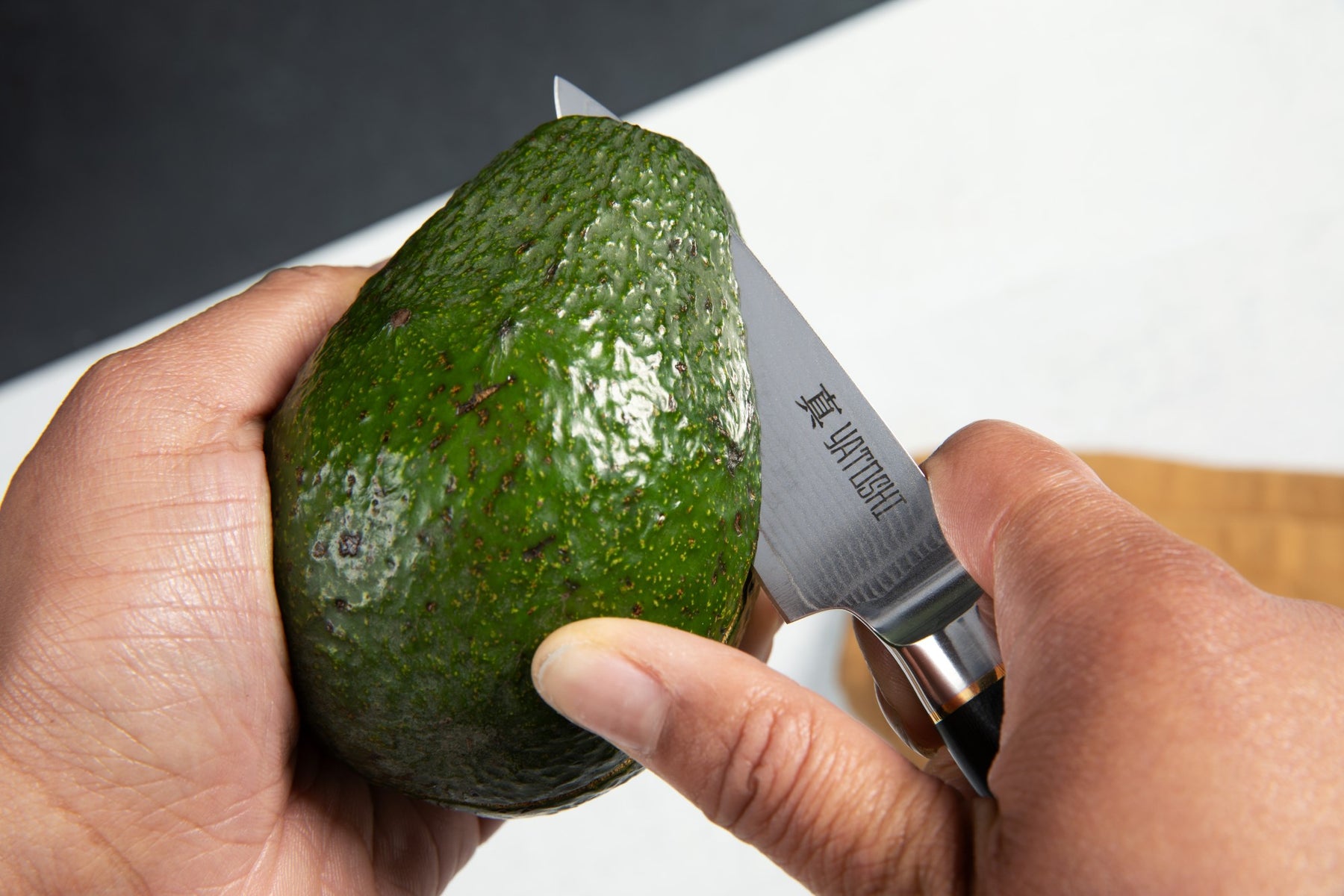 damascus paring knife slicing through an avocado