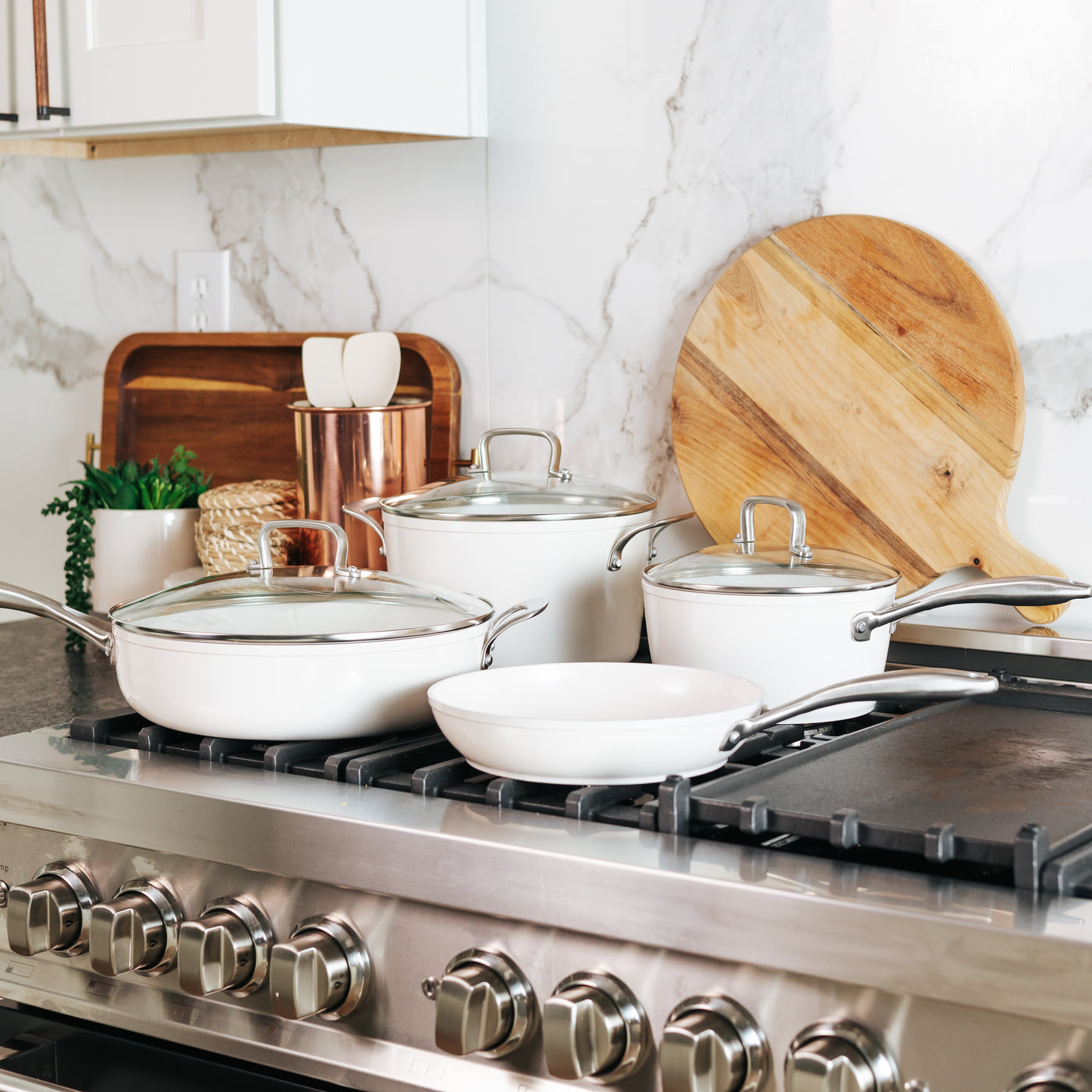 White cookware, frying pans and saucepans arranged in a bright kitchen